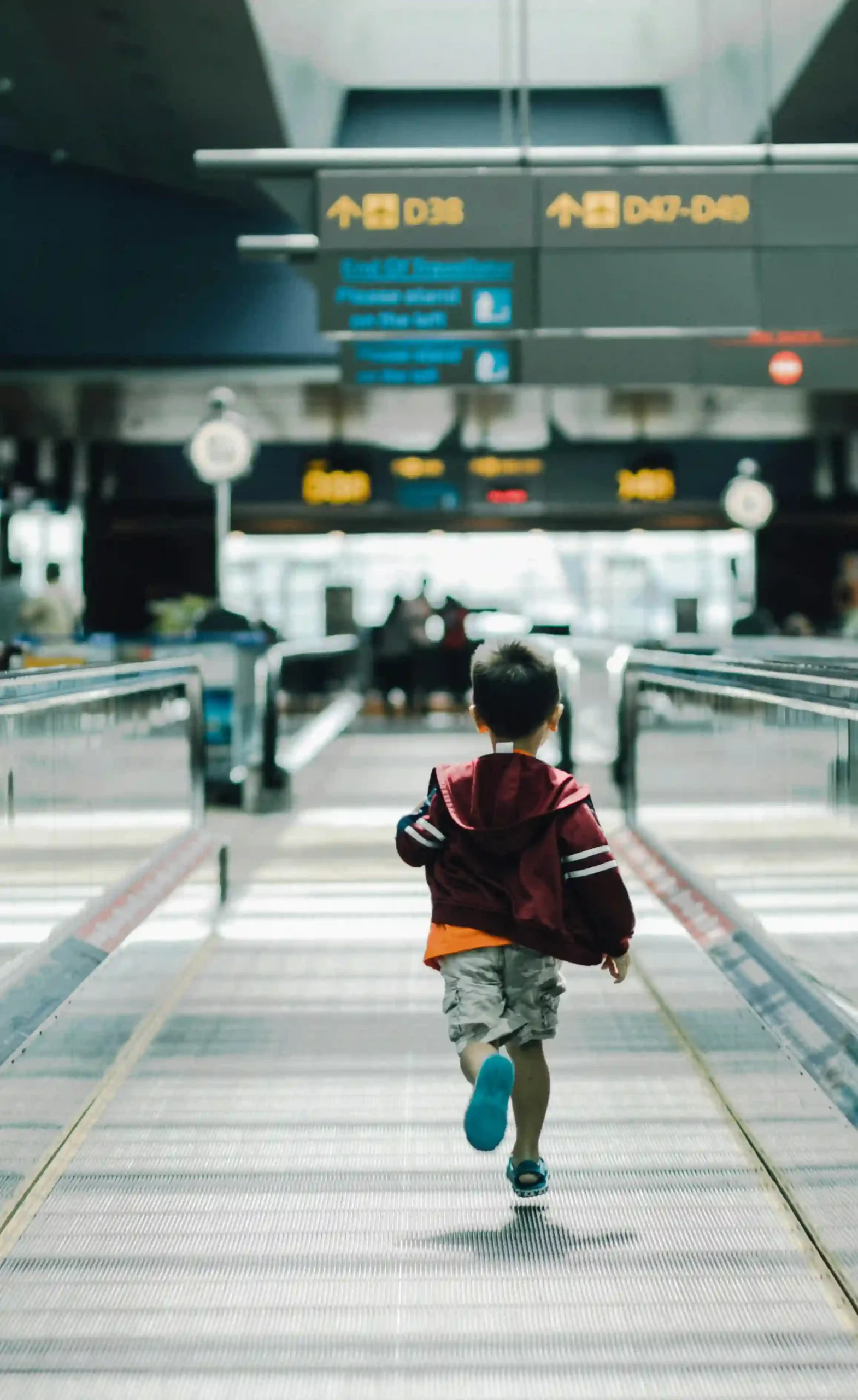 Menino de aproximadamente 5 anos correndo no salão de em aeroporto.