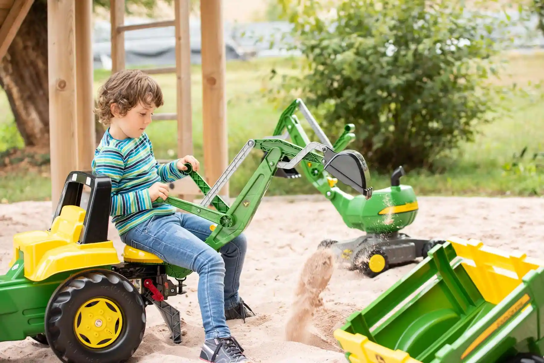 Menino branco de aproximadamente 6 anos brincando com trator infantil