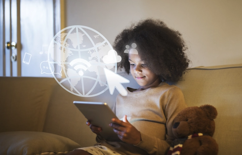 Uma menina negra de suéter bege, com cabelos cacheados, está sentada em um sofá, olhando para a tela de um tablet. Ícones digitais de conectividade, como um globo e uma nuvem, estão sobrepostos à imagem.