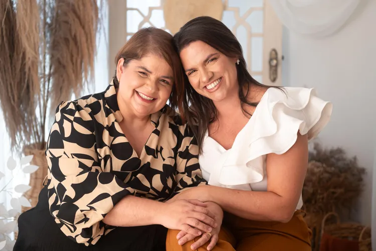 duas mulheres com a cabeça colada uma com a outra e segurando as mãos