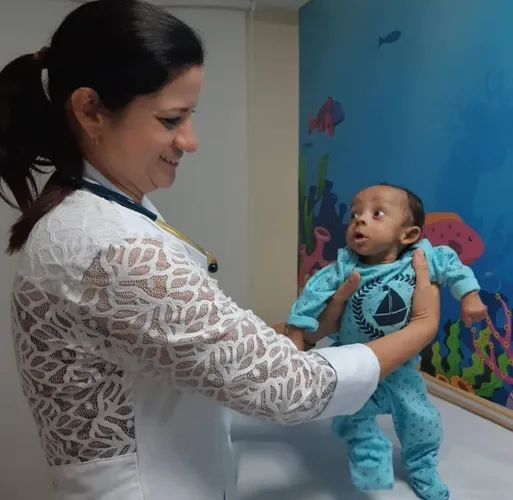 mulher vestida de branco segurando um bebê recém nascido de roupa azul