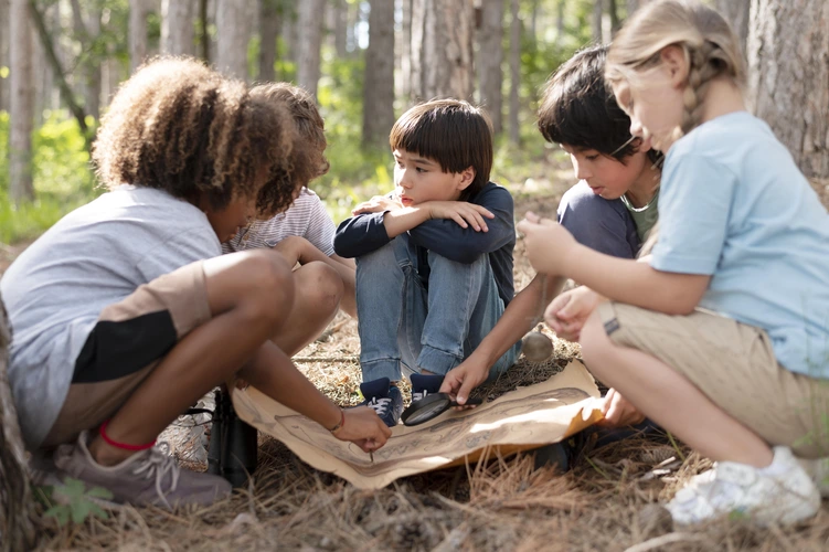 Crianças em grupo explorando a natureza durante uma atividade ao ar livre, observando elementos naturais e colaborando, em sintonia com a filosofia Reggio Emília.