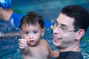 criança apontando o dedo para foto e homem vestido de preto segurando