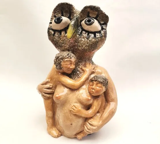 escultura de uma mãe-coruja grávida segurando dois filhotes
