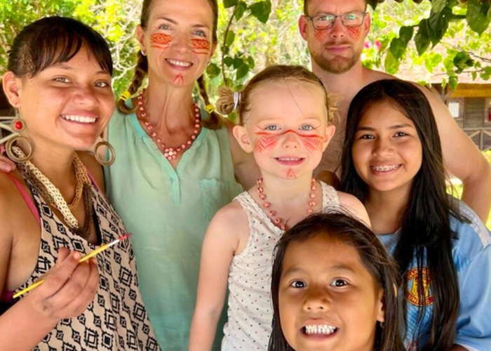 familia branca, formada por mulher, homem e criança, aparece sorrindo com mulher e duas meninas pardas.