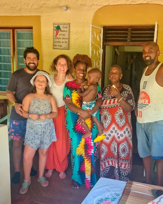 familia formada por homem, criança e mulher aparecem sorrindo junto a familia formada por homem, duas mulheres e criança negra. Todos estão sorrindo